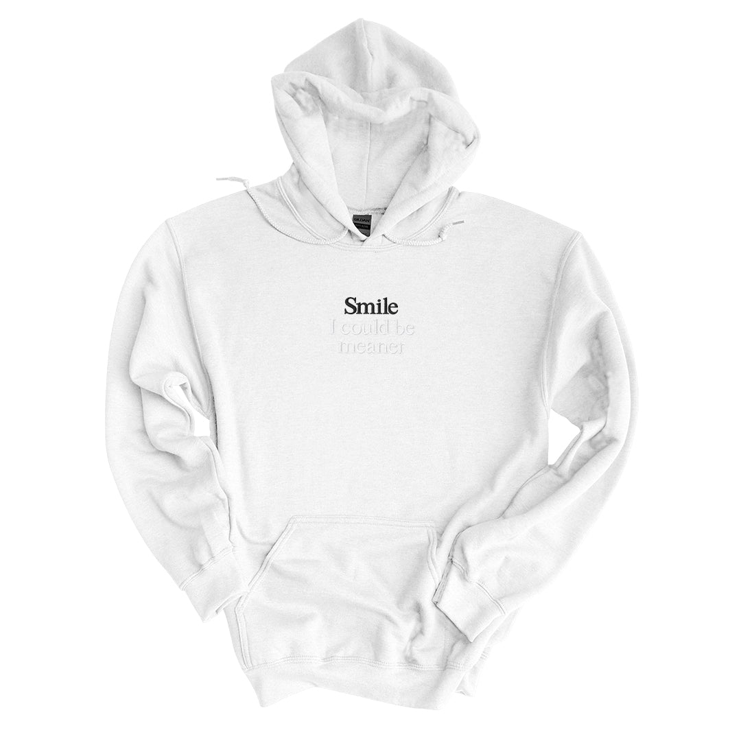 White hoodie embroidered with Smile in black thread and I could be meaner in tonal thread below