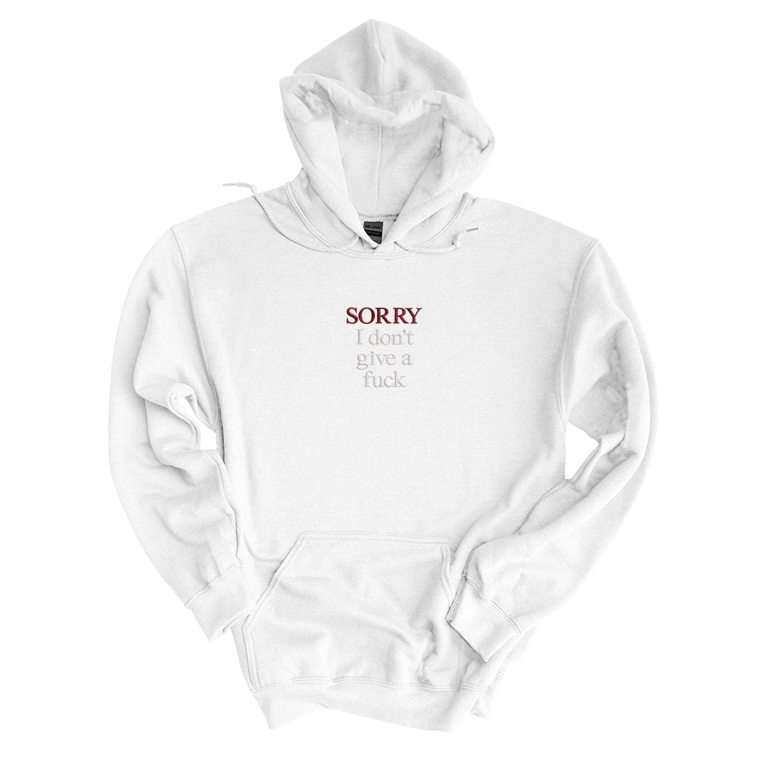 White hoodie embroidered with Sorry in black thread and I don&