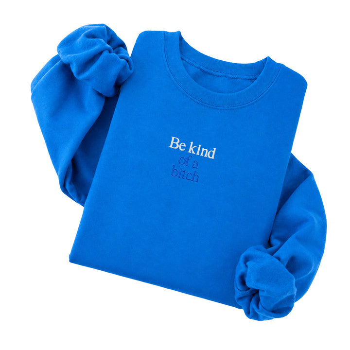 Sapphire crewneck sweatshirt embroidered with Be kind in white thread and of a bitch in tonal thread below