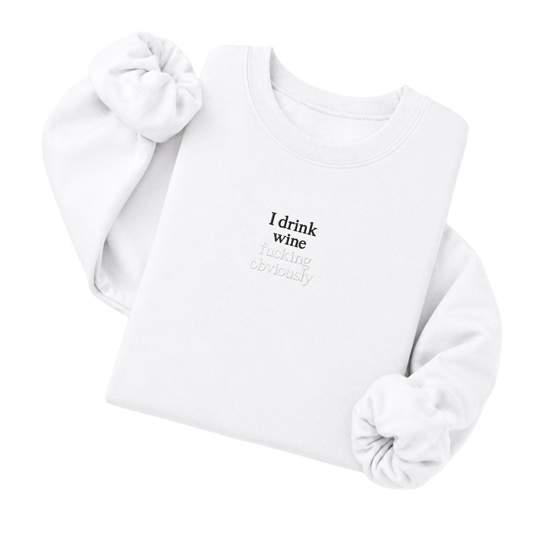 White crewneck sweatshirt embroidered with I drink wine in black thread and fucking obviously in tonal thread below