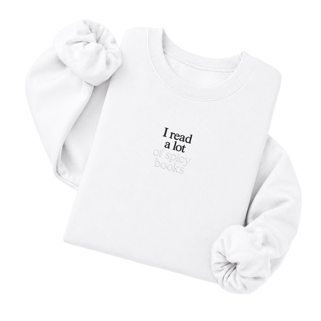White crewneck sweatshirt embroidered with I read a lot in black thread and of spicy books in tonal thread below
