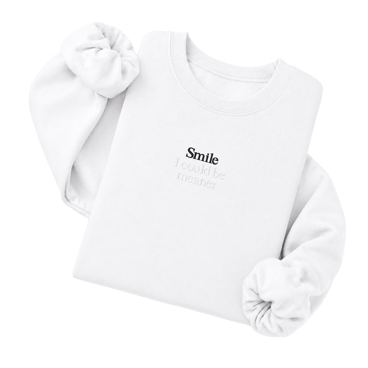 White crewneck sweatshirt embroidered with Smile in black thread and I could be meaner in tonal thread below
