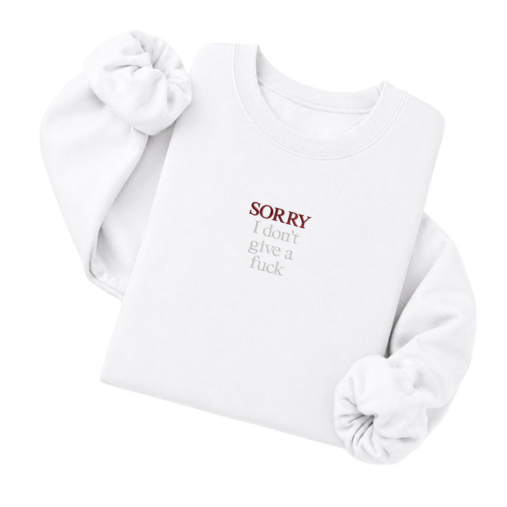 White crewneck sweatshirt embroidered with Sorry in black thread and I don&