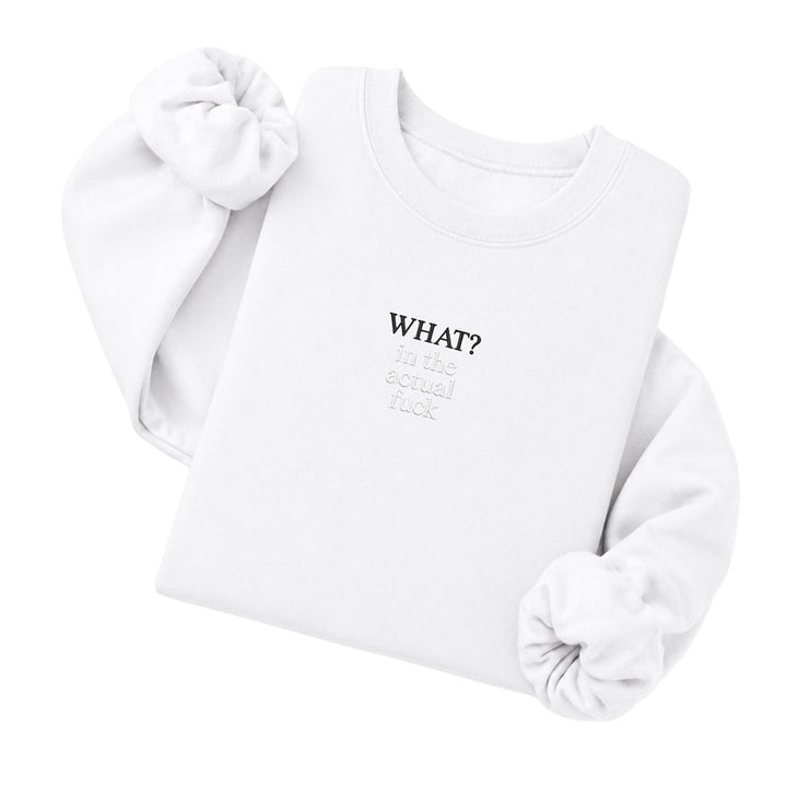 White crewneck sweatshirt embroidered with What? in black thread and in the actual fuck in tonal thread below